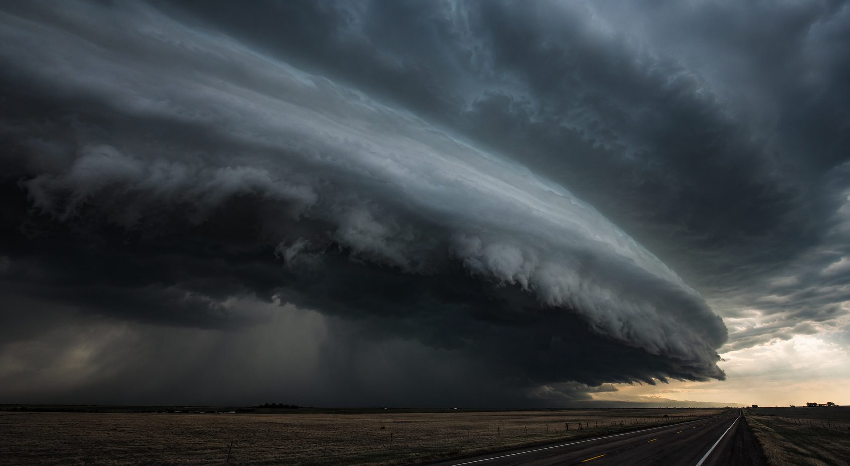 A shelf cloud advancing over open plains at dusk.